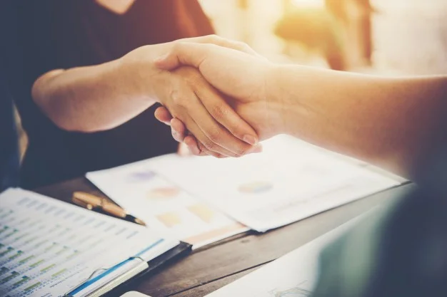 close-up-of-two-business-people-shaking-hands-while-sitting-at-the-working-place_1150-1816.jpg