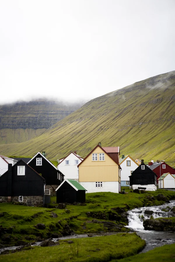 The small village of Gjógv is nestled in a valley in the mountains of the Faroe Islands. Many villages, such as this one, are home to no more than 100 people, often from the same family unit. This particular village has no grocery store or gas station — its only buildings that are not houses include an old church and an indoor fish farm.