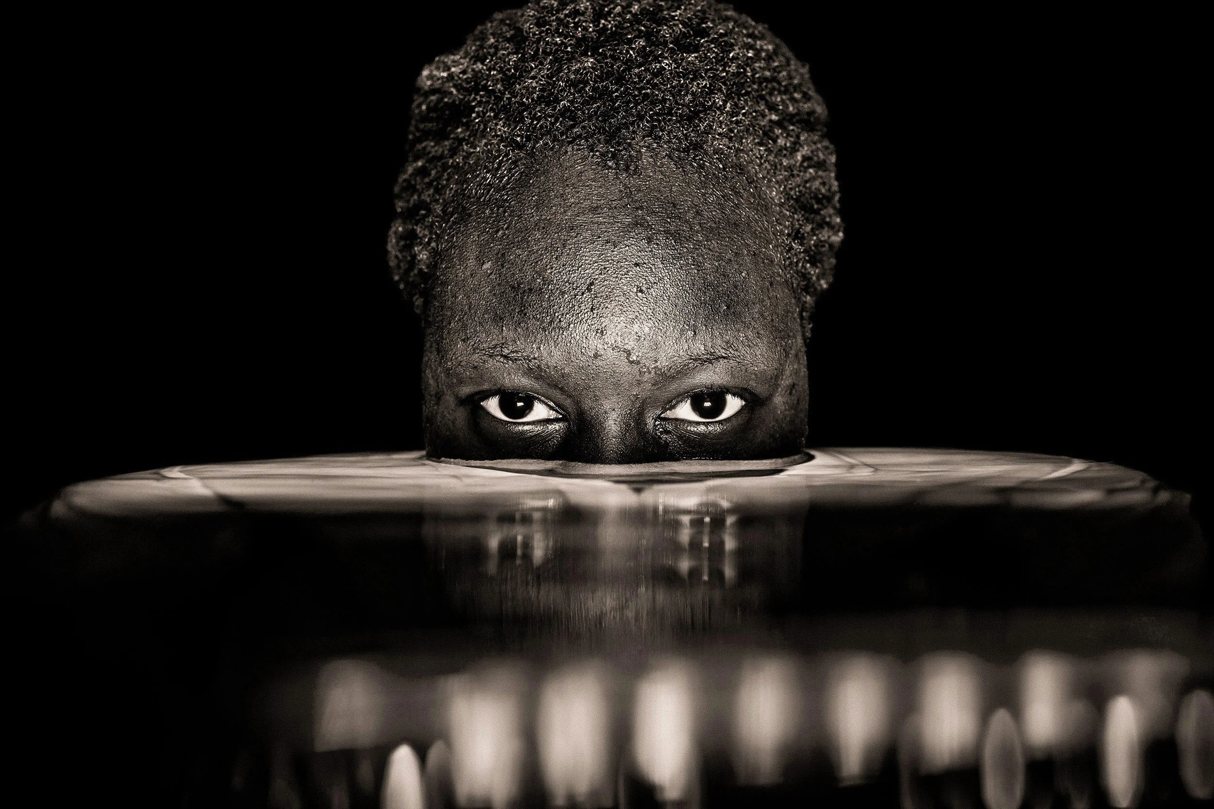 A stunning captivating portrait, with eyes gazing just above the waters surface where a reflection of light dances, photography fine art by Ted Grambeau.
