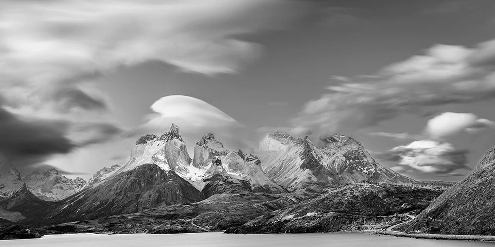 Black-and-white long-exposure panorama of Torres del Paine peaks and soft drifting clouds, Patagonia.
