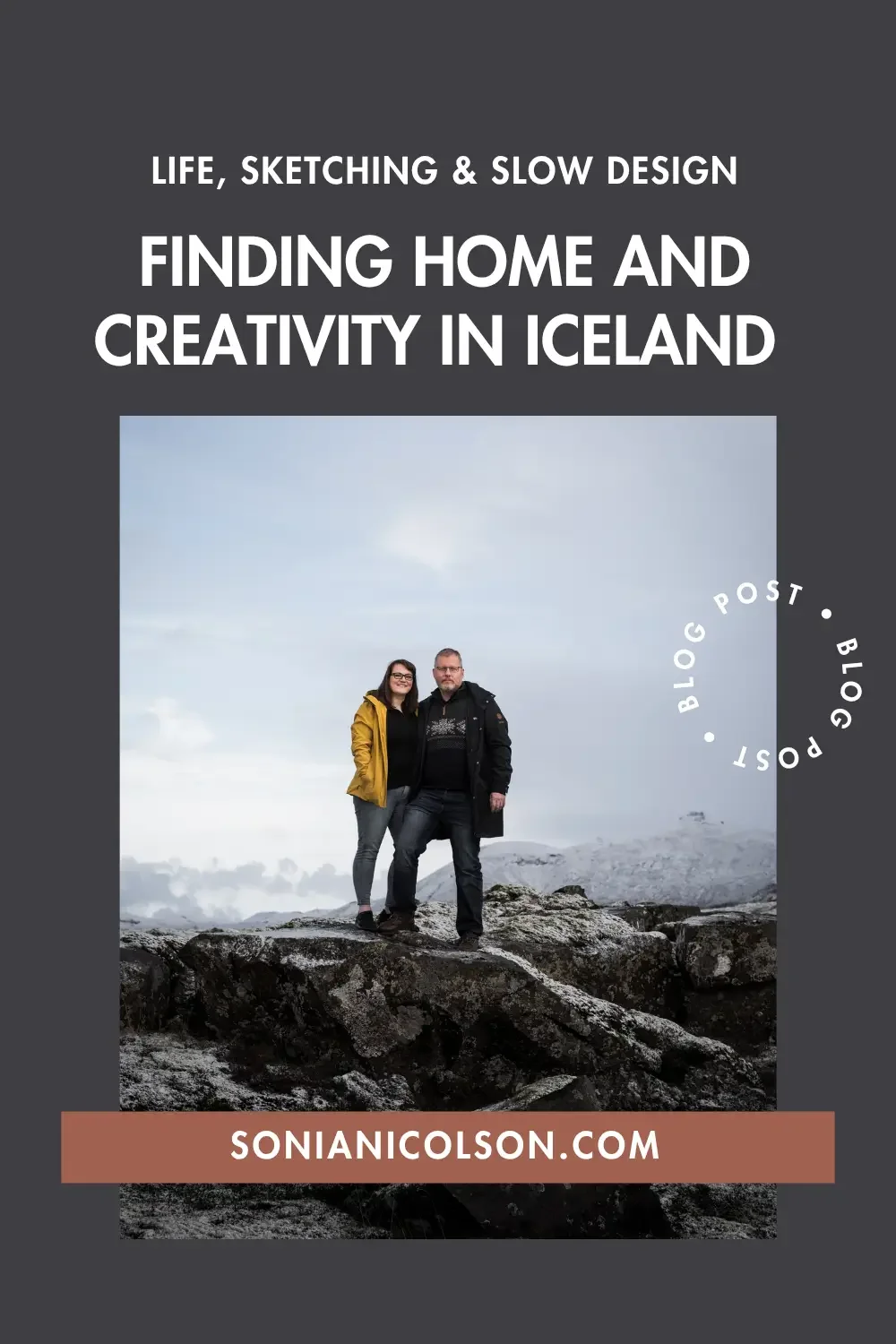 Sonia and her husband standing on a rocky Icelandic landscape with snow-capped mountains in the background.