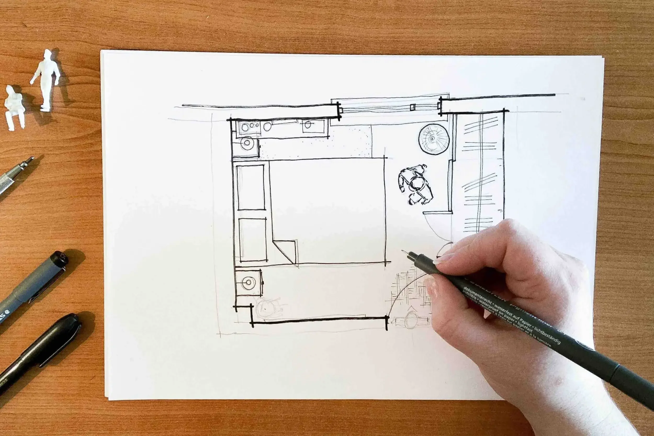 Hand-drawn interior floor plan with furniture, doors, and windows sketched in pen on white paper