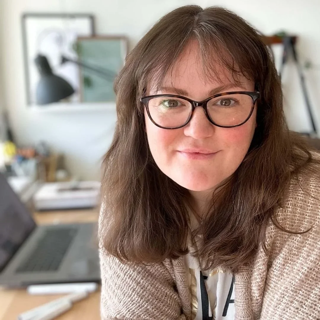 Sonia Nicolson, female architect, educator, and mentor – smiling at her desk in a cozy home studio. Known for helping women in architecture and design build creative, fulfilling careers through hand-drawing, mentoring, and education
