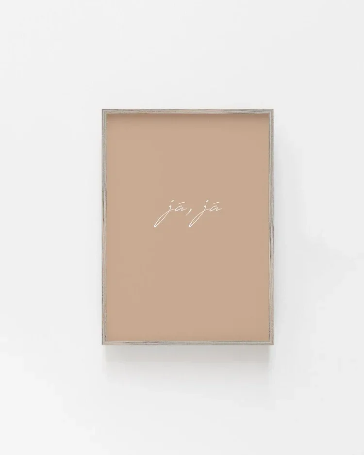 Framed minimalist Icelandic typography print with the phrase “já, já” in delicate white script on a warm neutral background, Scandinavian style wall art.