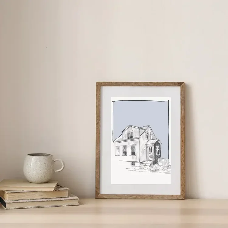 Framed digital architectural drawing of a traditional house on Frakkastígur in Reykjavík, Iceland, styled on a wooden shelf with books and a ceramic mug.