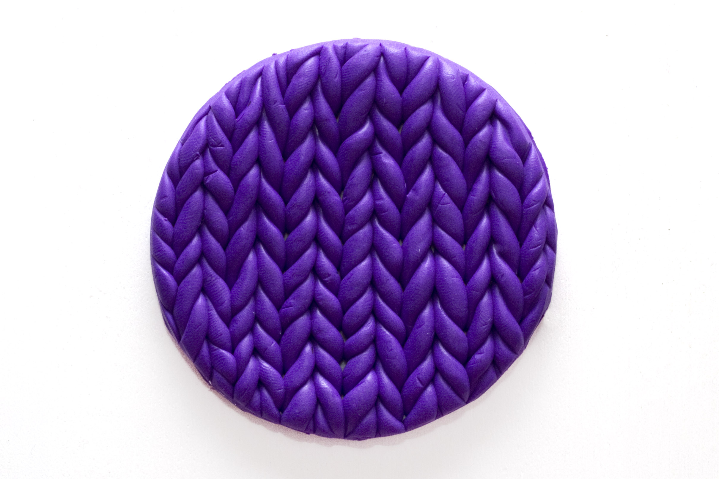 Step 3: Once you have attached all of the rolls of fimo, use the top of the glass to cut the design into a circle. If the top of your glass is smaller than you want your coaster to be, use a knife or cutting tool to carefully cut the shape. This will be the shape of your fimo clay coaster.