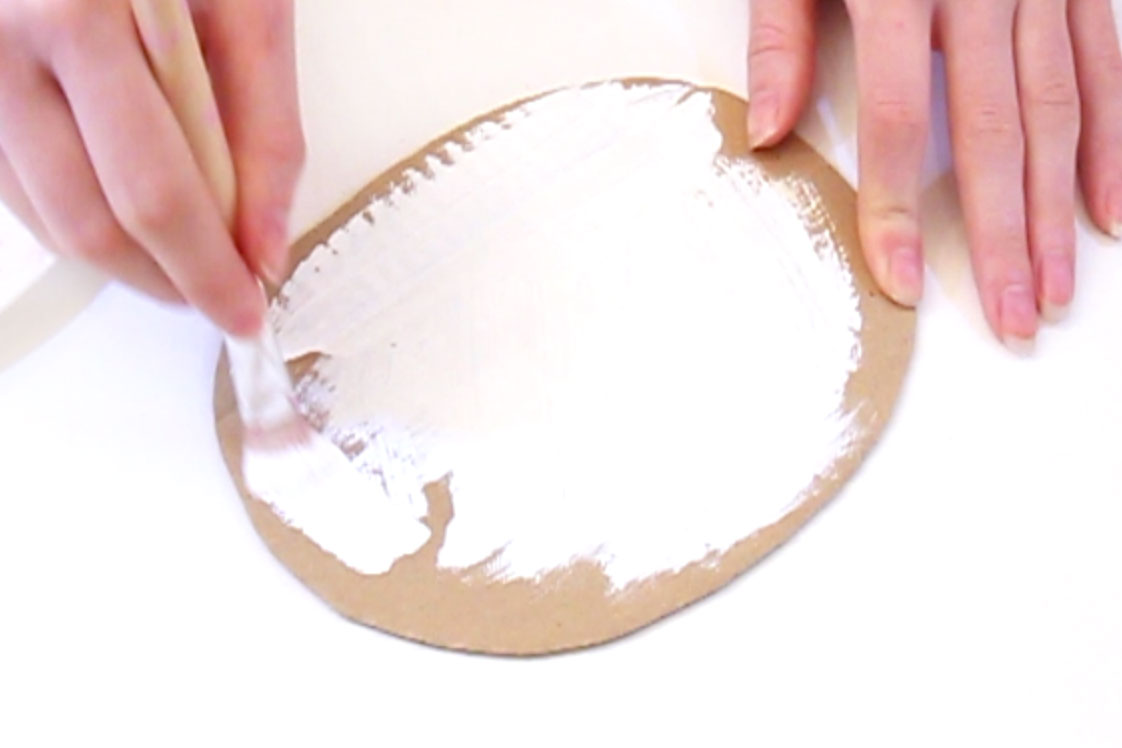 Step 2 Cut out an oval shape from the cardboard, approximately 18cm by 14cm. Paint this piece of cardboard white and leave to dry.