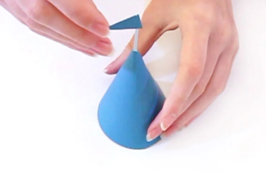 Step 4 Push the cocktail stick into the top of the cone, glue in place if necessary. Then cut out a flag shape from the blue paper and glue to the cocktail stick.