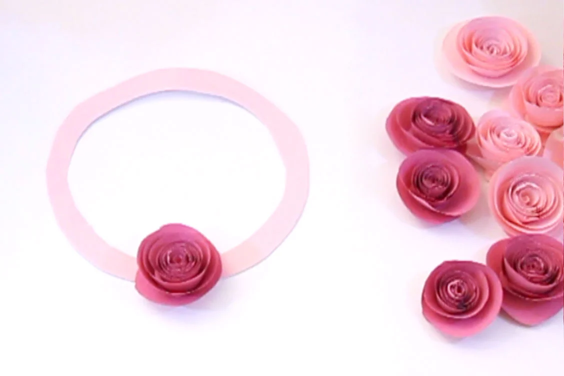 Step 5 Cut a circle out of a piece of card, and cut another circle inside that to create a ring. Then use the glue gun to stick the paper roses onto the card, and your wreath is complete! Add ribbon to the top if you want to hang it up. Subscribe to my newsletter to receive fun craft ideas weekly! Please note: this blog post contains affiliate links, however all opinions are my own and I only link to products that I personally use and recommend. Here's a video showing you how to make these paper roses. Subscribe to my youtube channel for more crafty videos!
