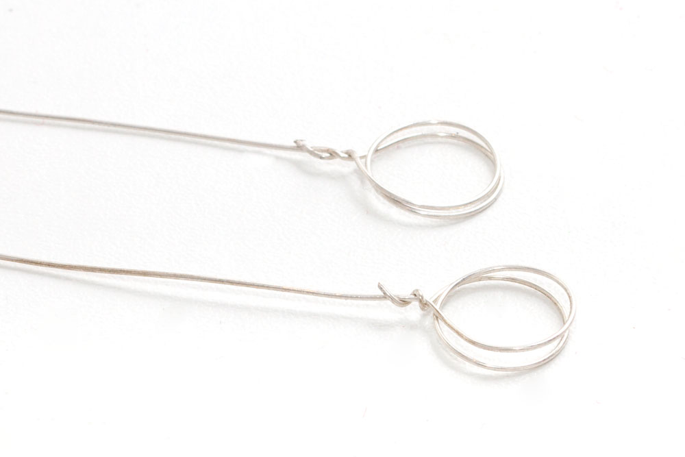 Step 2 Using the pliers, twist the end of the wire twice round a pen (you could also use your finger or something else that is round and a similar size). Leave a small bit of the wire at the end to wrap around the longer piece of wire to hold it in shape. Make sure the two circle are pushed tightly together as they will be holding the photo/name card.
