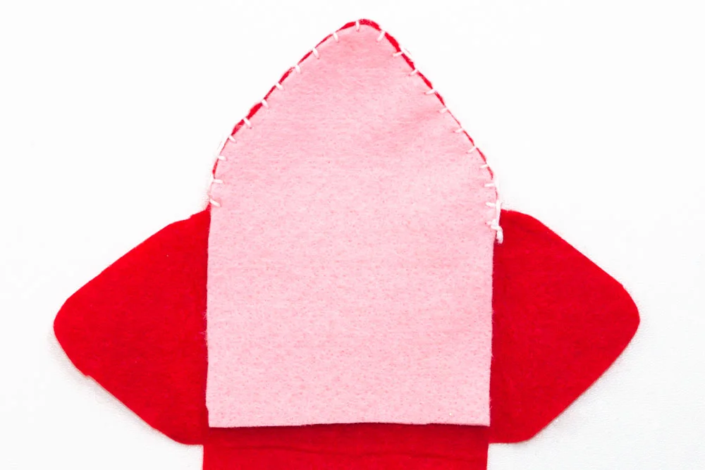 Step 3 Turn the piece of red felt over so that the stamp is facing the table. Then place the pink piece of felt over the top of the red piece and stitch together using a blanket stitch. Only stitch the upper part of the felt as you don't want the stitch showing through on the front of the envelope.
