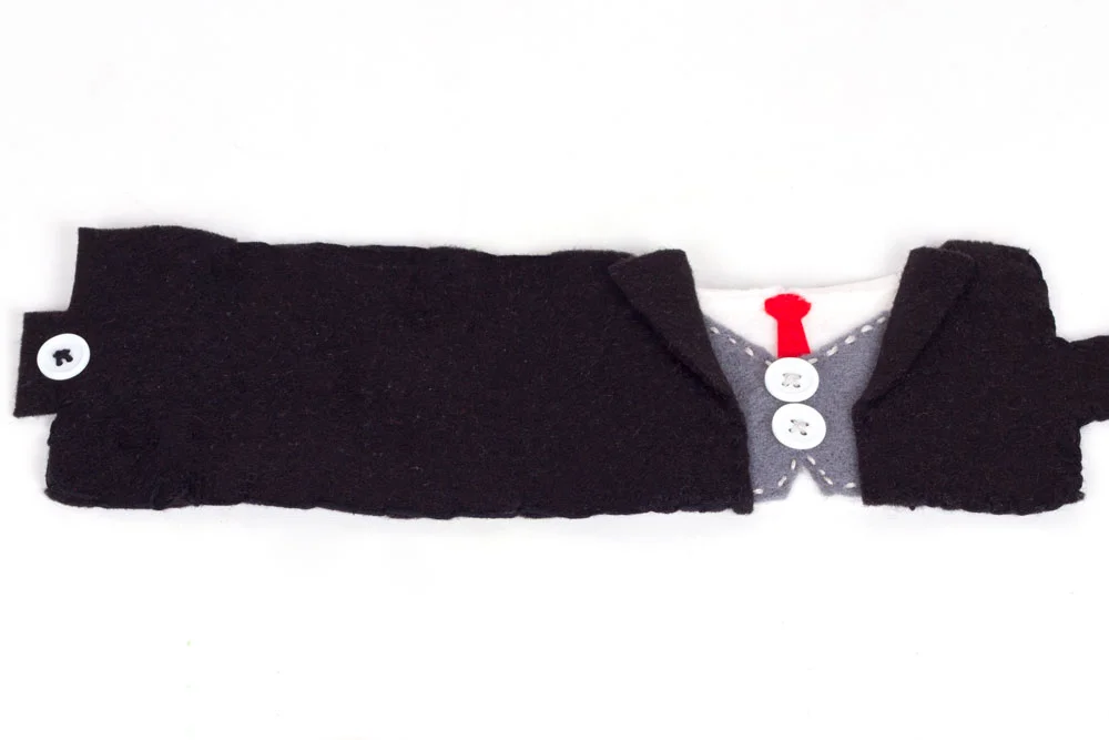 Step 3: Using the black thread, sew the two black pieces of felt either side of the grey, about 1cm away from the buttons. Cut a button hole in the black felt on the right hand side, and sew a button onto the left hand side. 