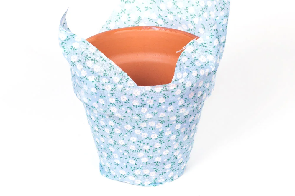 Step 2 Place the material over the area of the plant pot that is covered in mod podge. Use your fingers to smooth out any wrinkles and to ensure the material is completely stuck down.