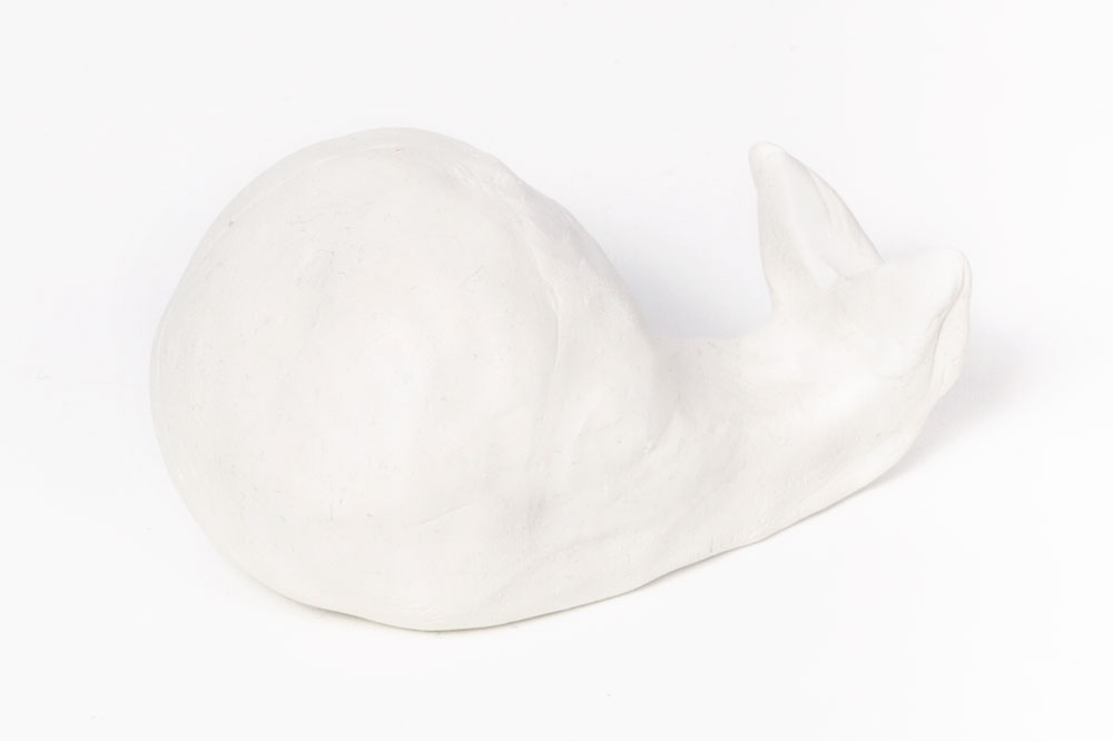 Step 1: Take a large section of the air dry clay and mould into the shape of a whale using your hands. In order for it to hold the phone upright the whale's head will need to be quite round and the tail will need to curve upwards - similar to the shape in the image above. Smooth out any creases or wrinkles and leave the clay to dry overnight. It will help to prop the tail up with something so that it doesn't drop when drying.