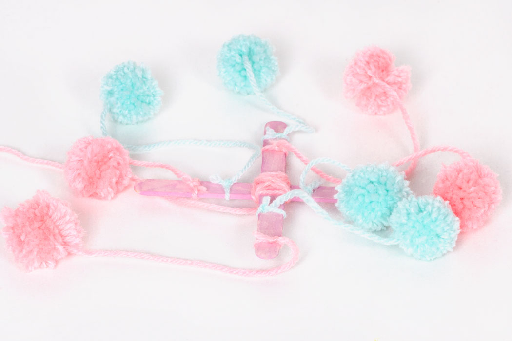 Step 3 Tie the pom poms onto the lolly stick cross. Tie two pom poms to each side, at varying lengths. Then trim the remaining ends of the wool. As there are equal amounts of pom poms on each side, the mobile should hang evenly. Subscribe to my newsletter to receive fun craft ideas and freebies!