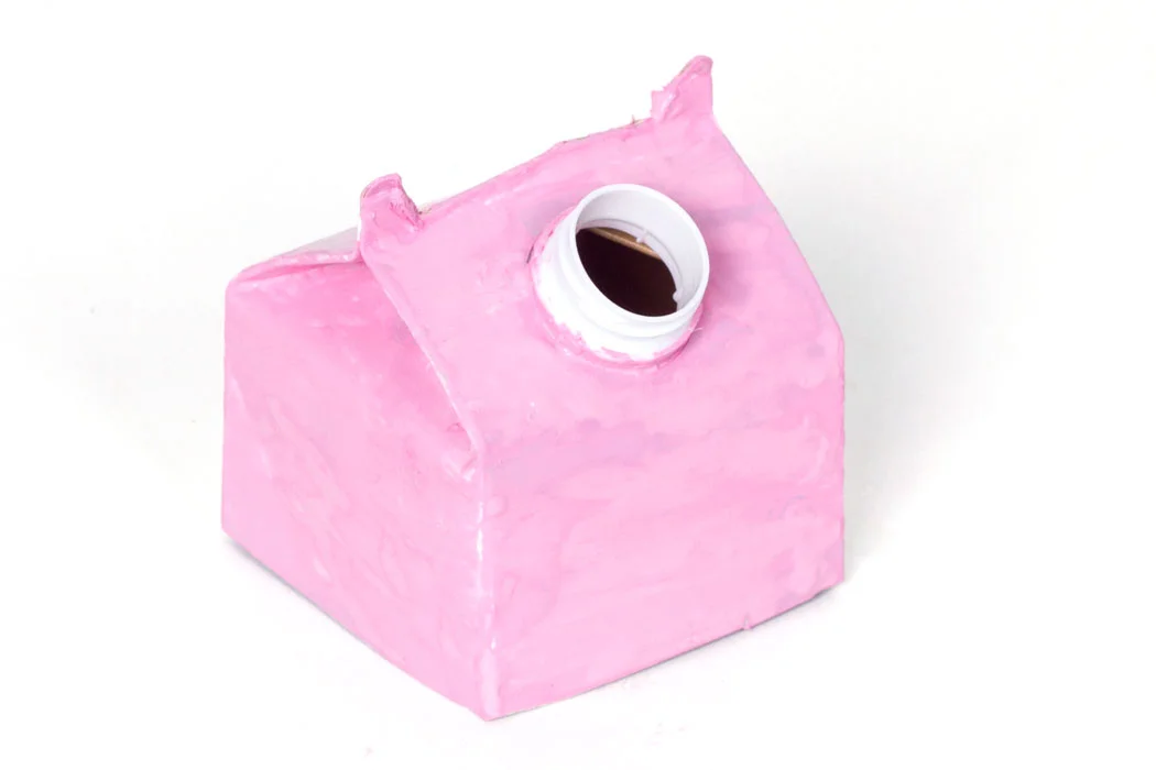 Step 3 Cut two ears into the top of the juice carton, and then take the lid off. Cover both the lid and the carton in light pink paint and leave to dry. Depending on the colour of your juice carton it may need a few more coats of paint.