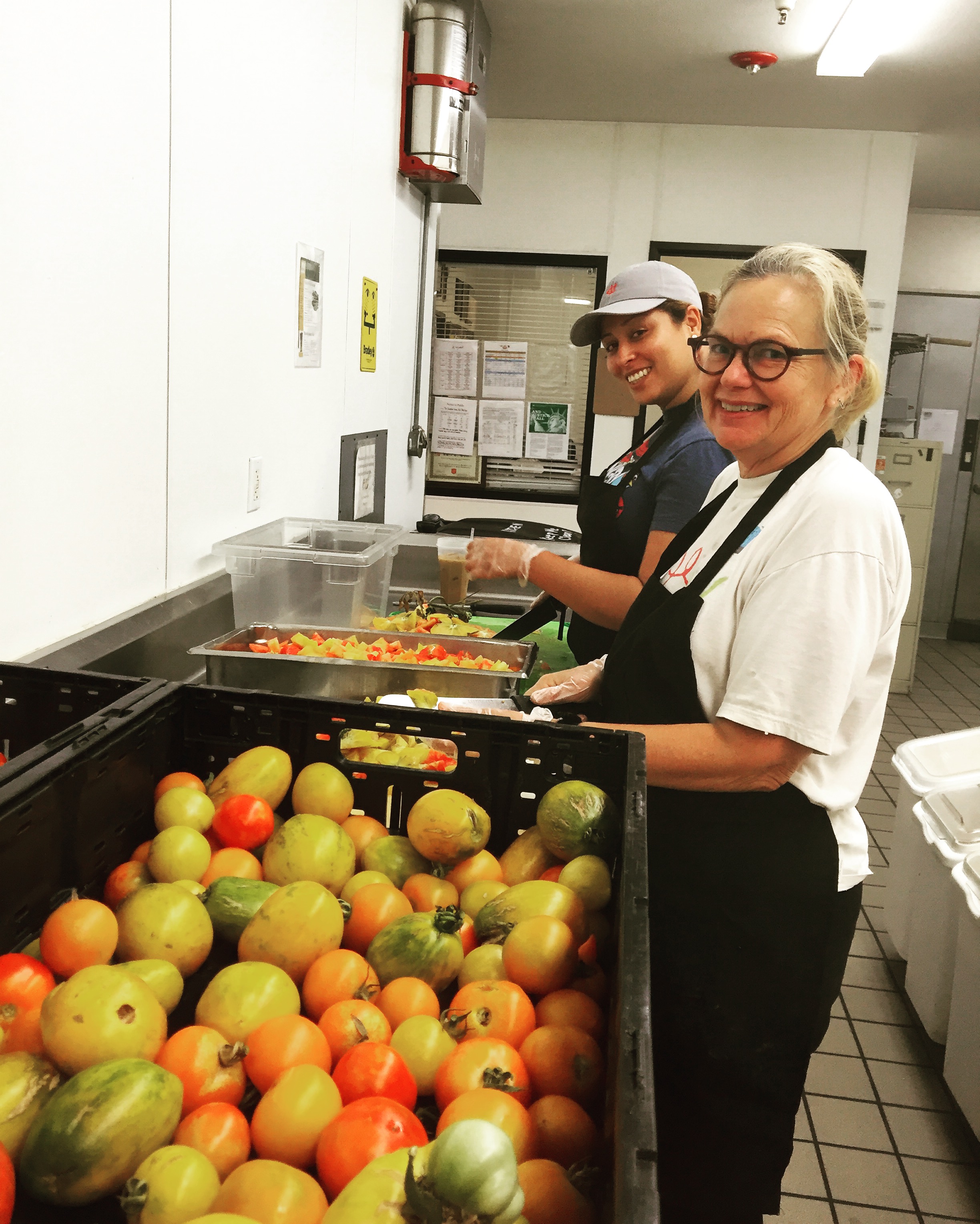 Mary and kitchen staff member slicing tomatoes. 
