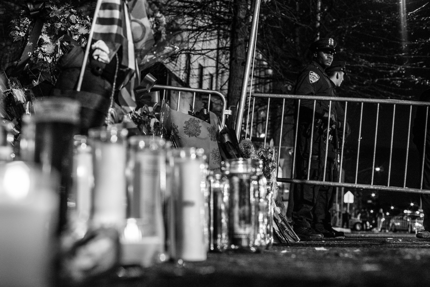 NYPD officers Wenjian Liu, 32, and Rafael Ramos, 40, were sitting in their police car parked near Myrtle and Tompkins avenues in Bedstuy, Brooklyn when both were shot through the window by an attacker claiming to be reacting to the decision not to acquit police for their involvement in the death of Eric Garner. Flowers and candles mark the spot as NYPD officers look on. This happened in the same neighborhood as the boxing gym that Nate manages.