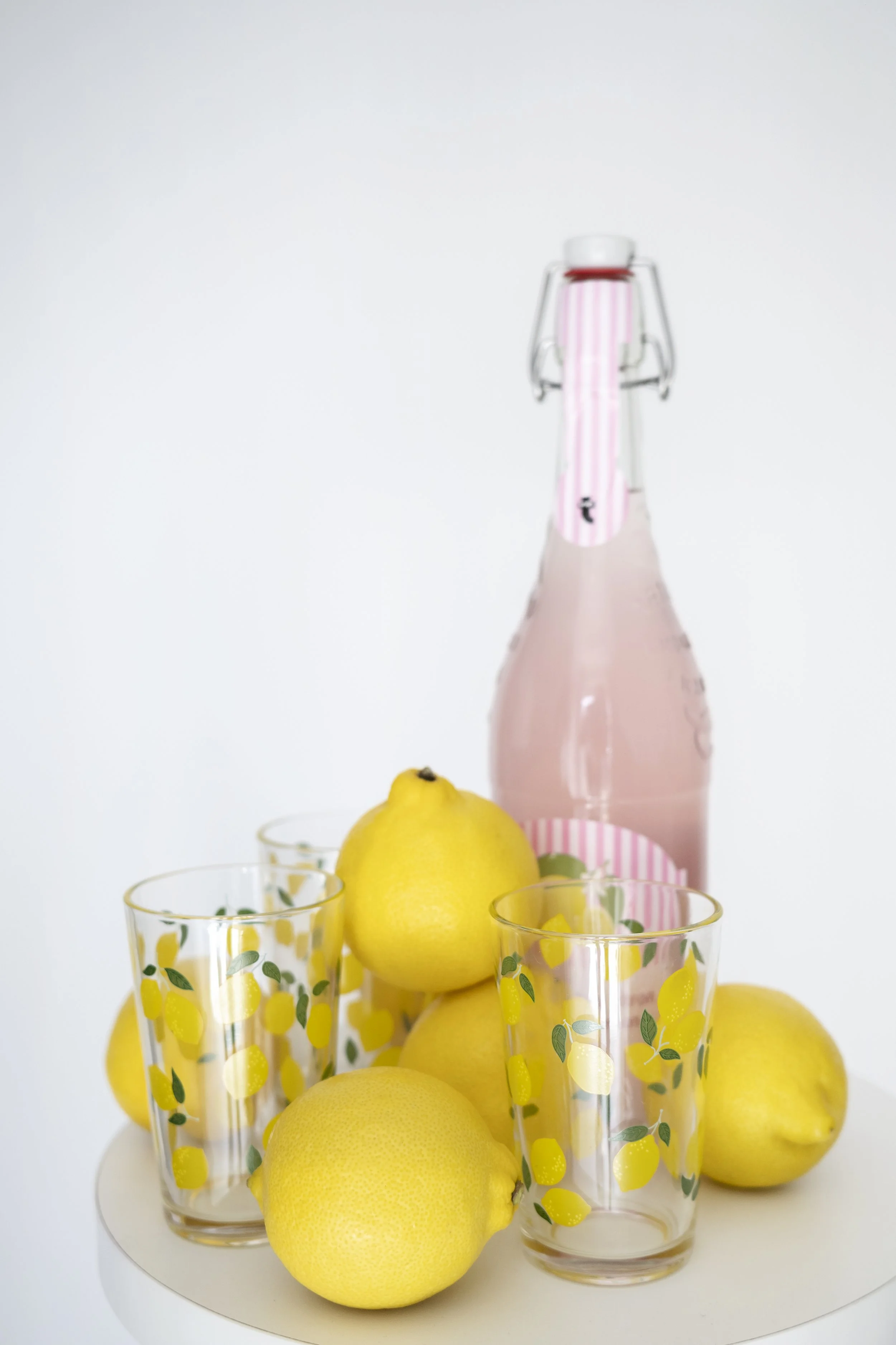 Lemons next to a lemon glass and a bottle of pink lemonade