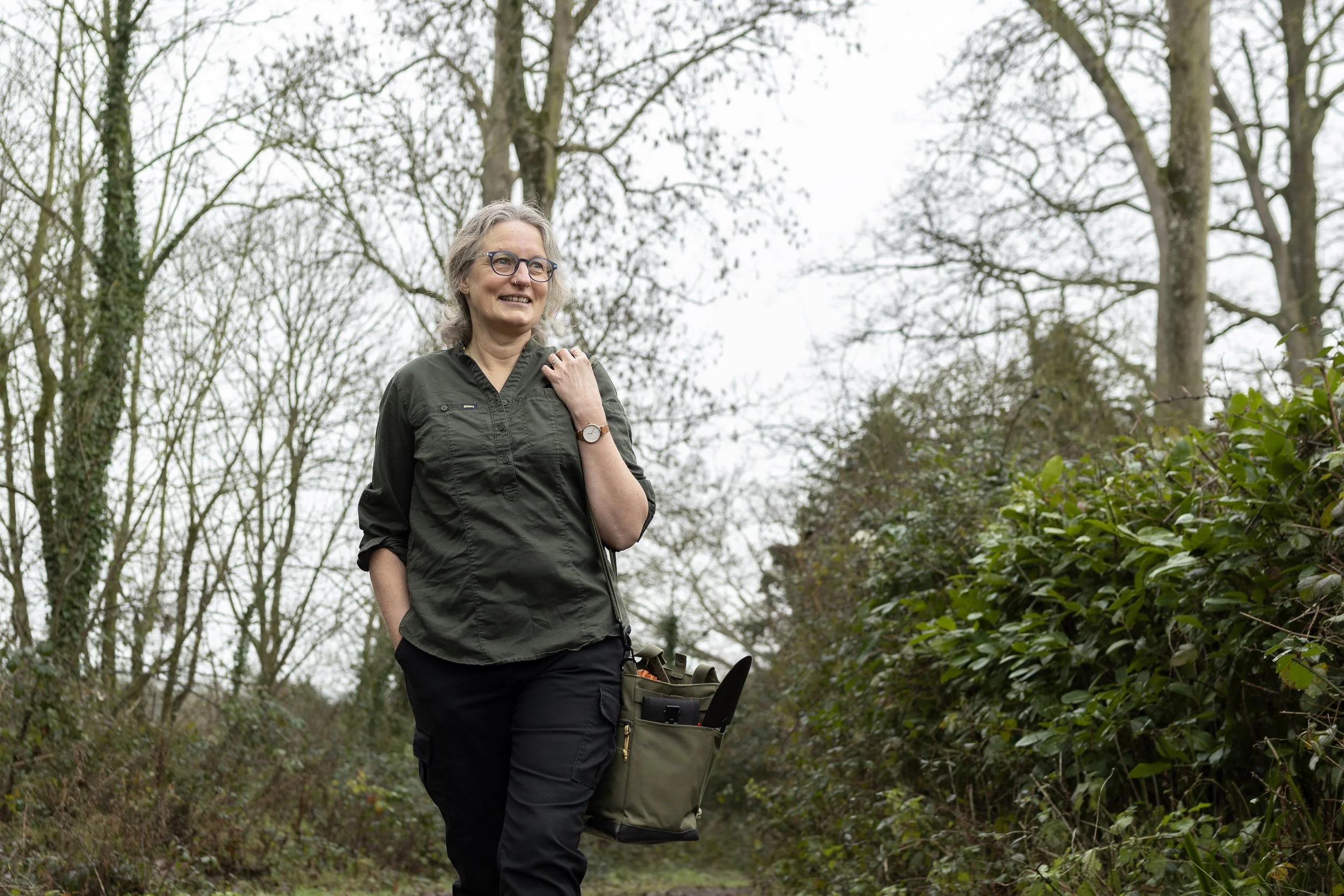 A gardener midwife out for a walk looking at the plants with her tool kit