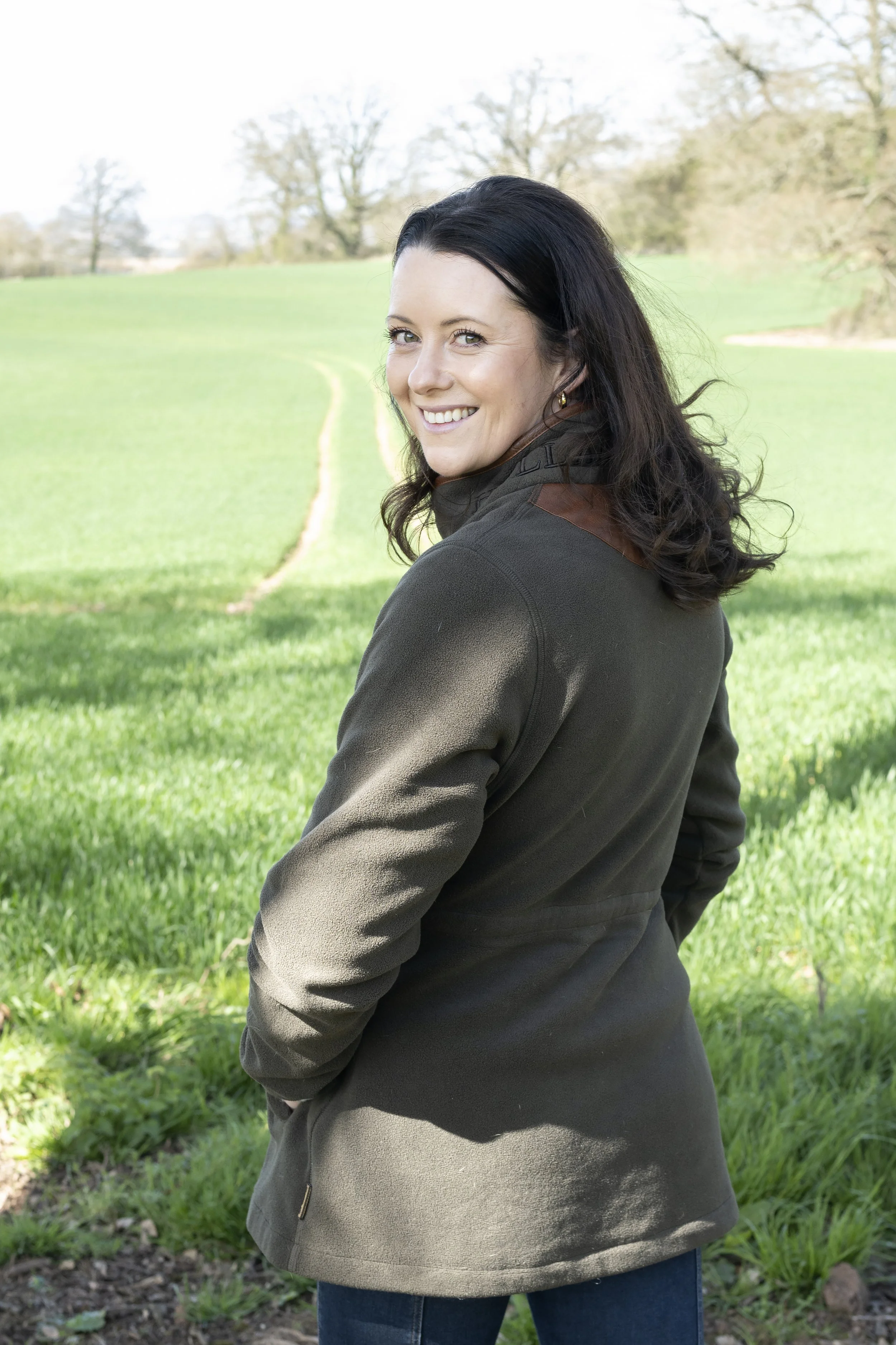 Estate planner in the field looking over her shoulder smiling at the camera