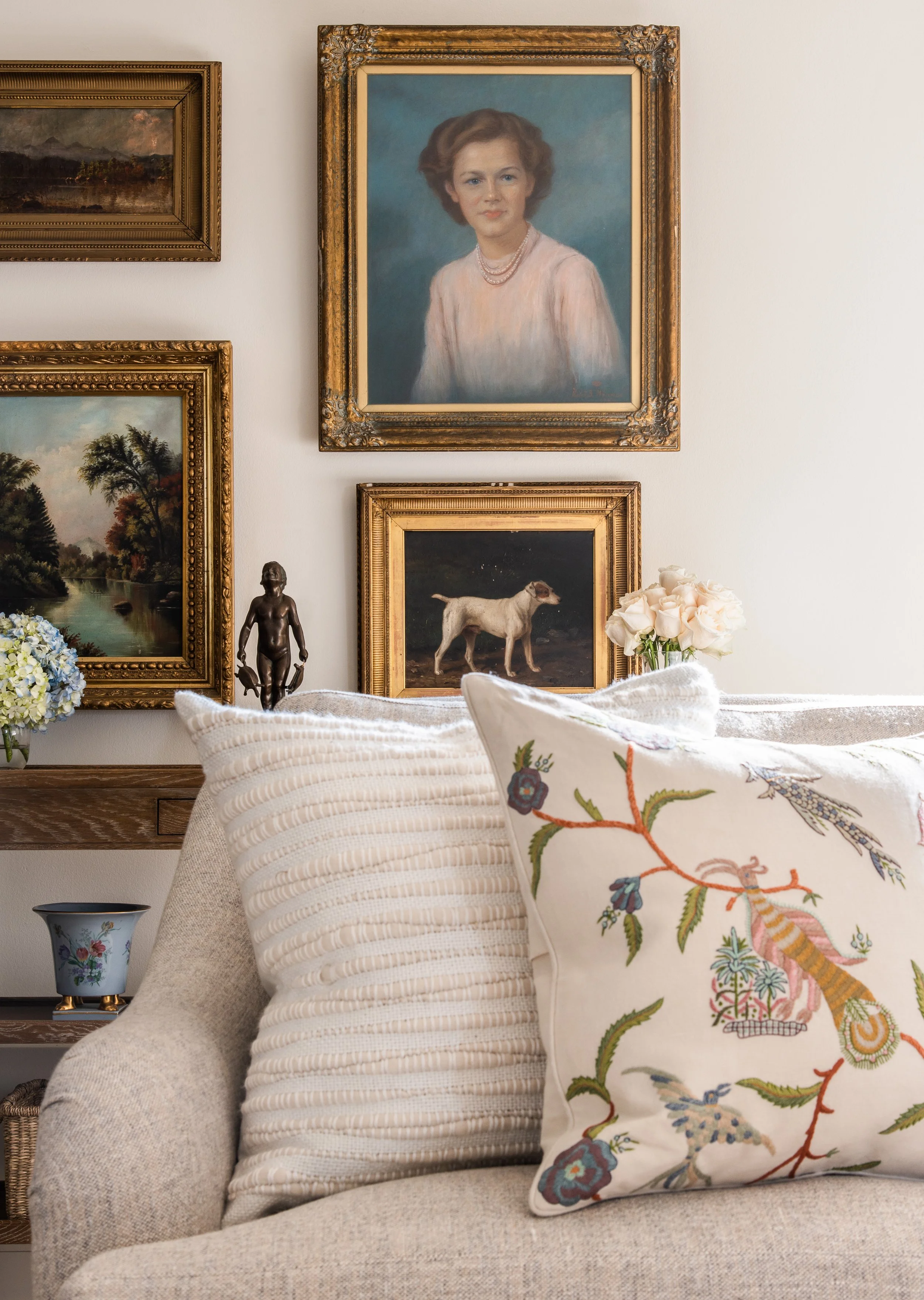 Gallery wall with four framed paintings behind couch.