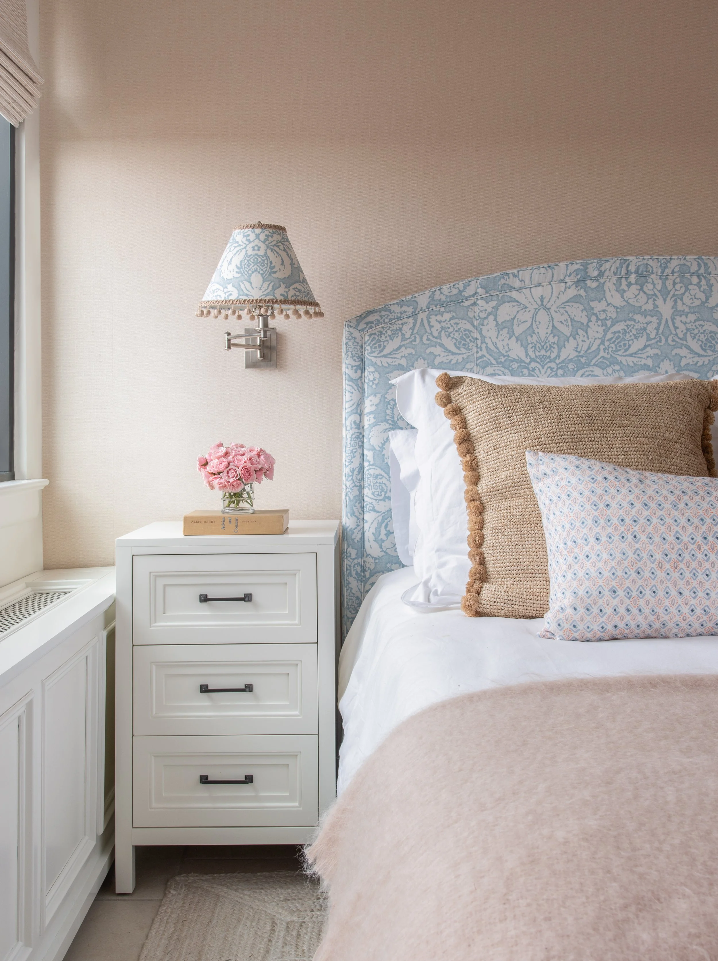 Bed with blue and white bed frame, white bedside table, and mounted lamp with blue pattern.