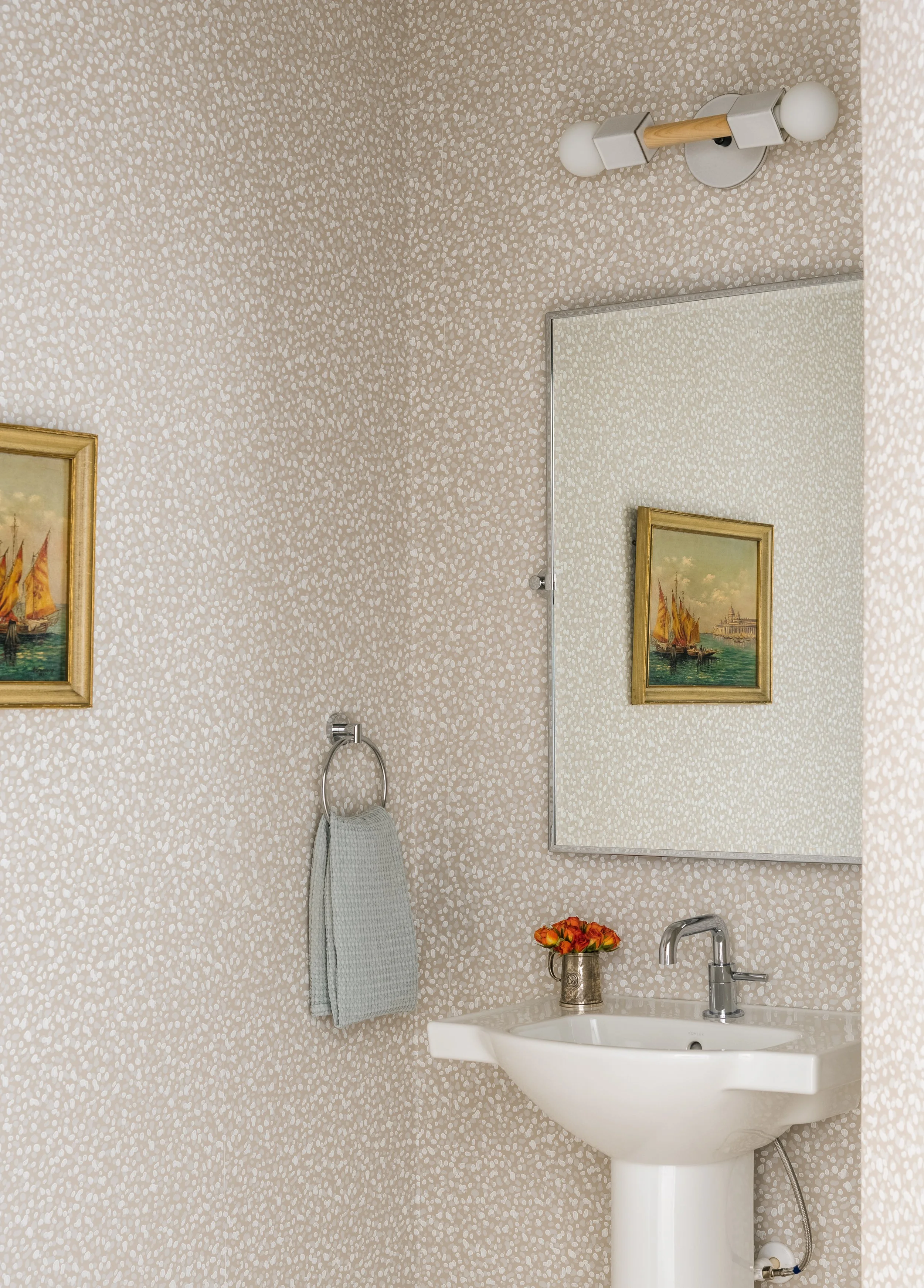 Restroom with beige speckled wallpaper, sink, and rectangular mirror.