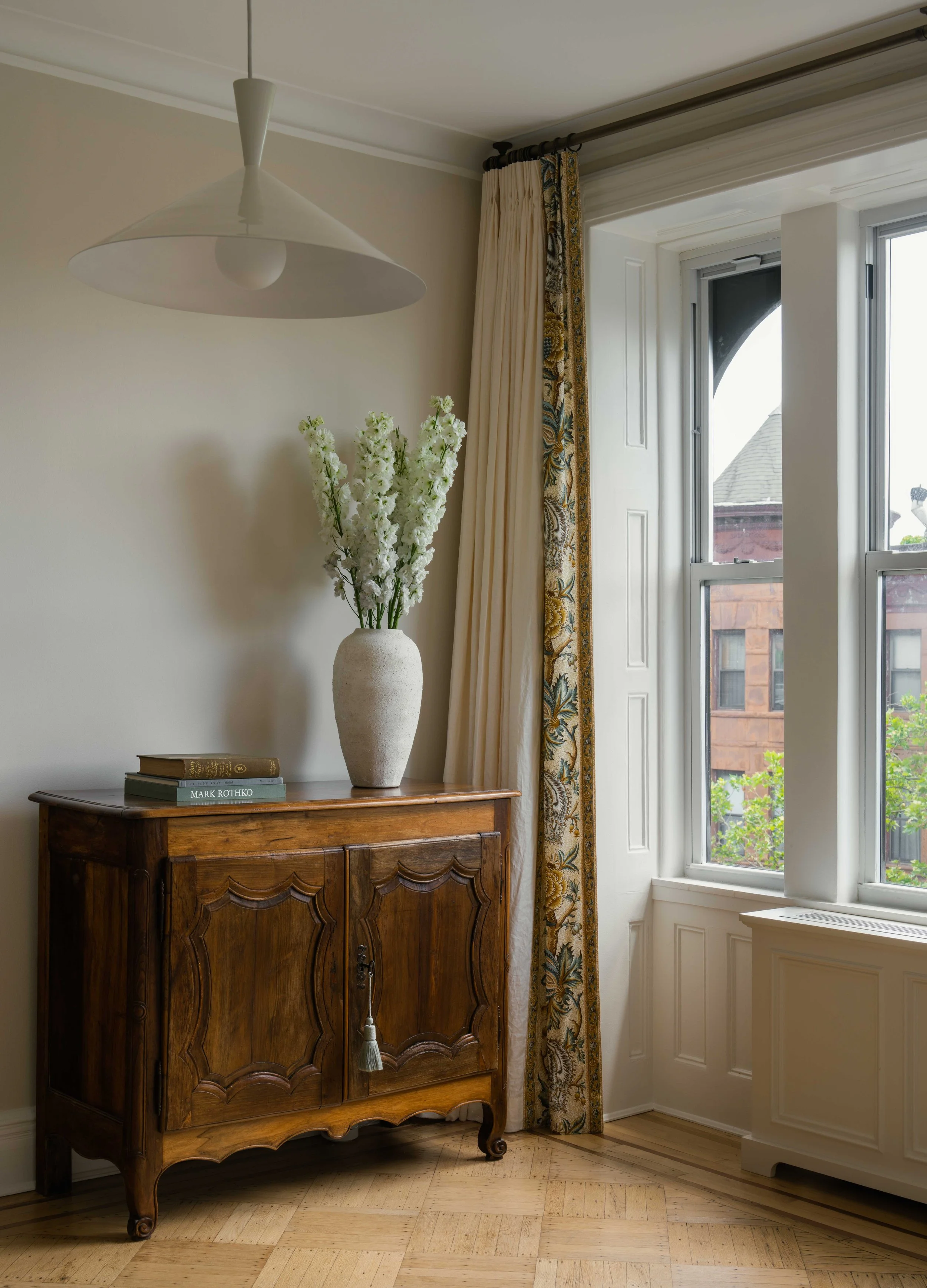 Wooden console with large plant vase and books.