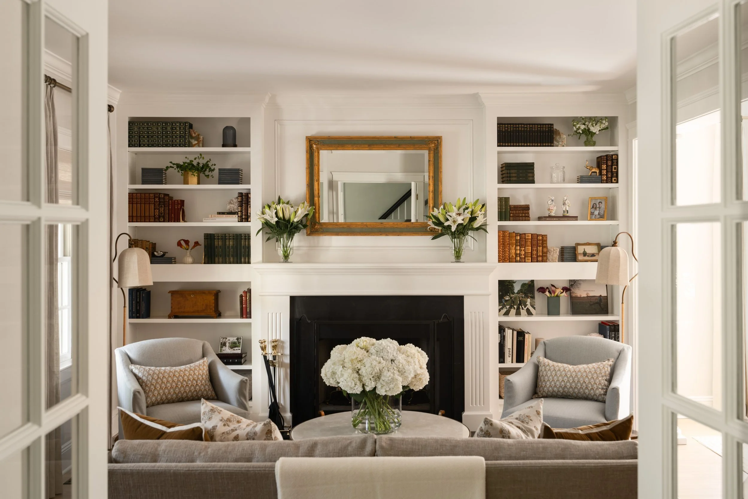 Bright, symmetric living room space with built in shelves, fireplace, and seating.