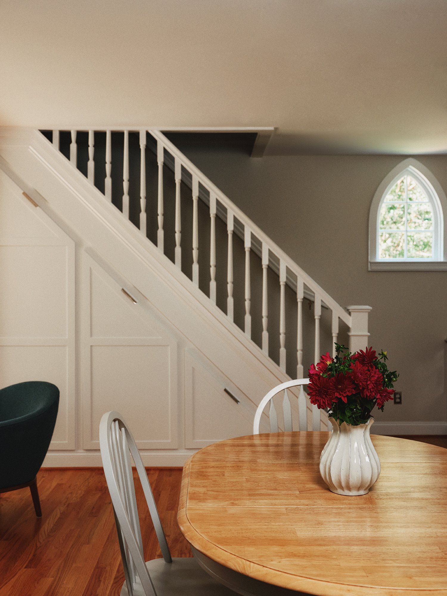 Wooden dining table next to white staircase.