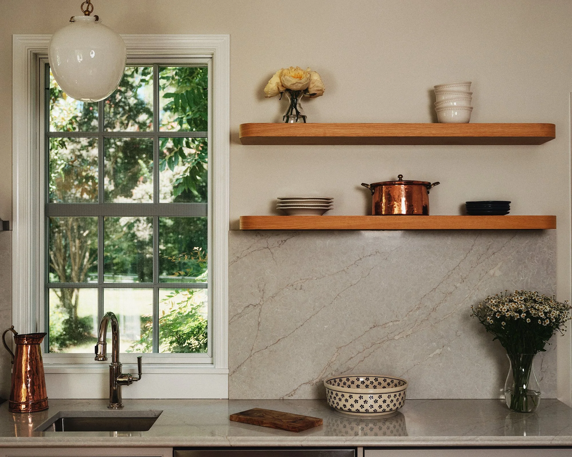 Kitchen sink with window and wood shelves.