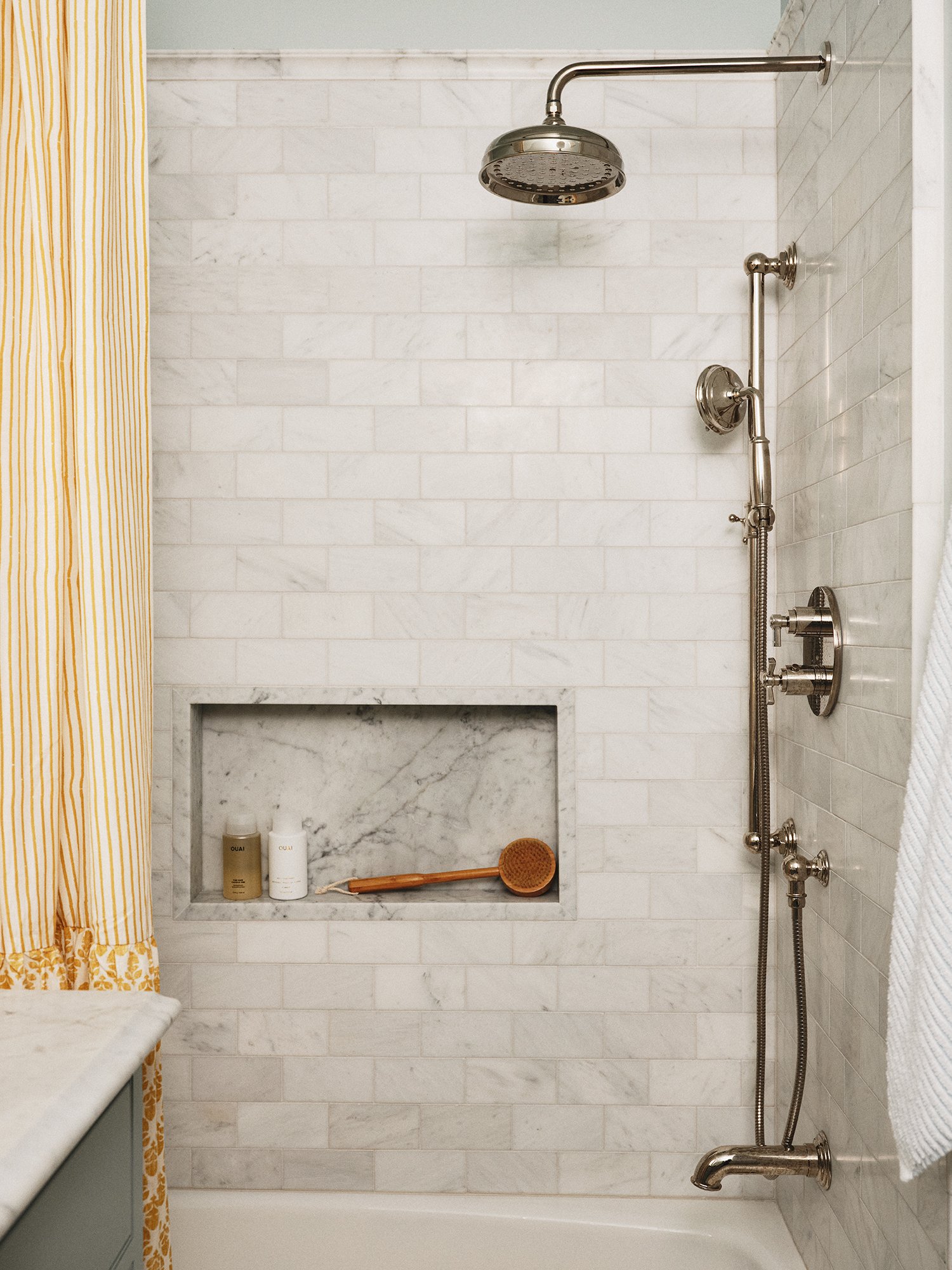 White-tiled shower with yellow curtains.