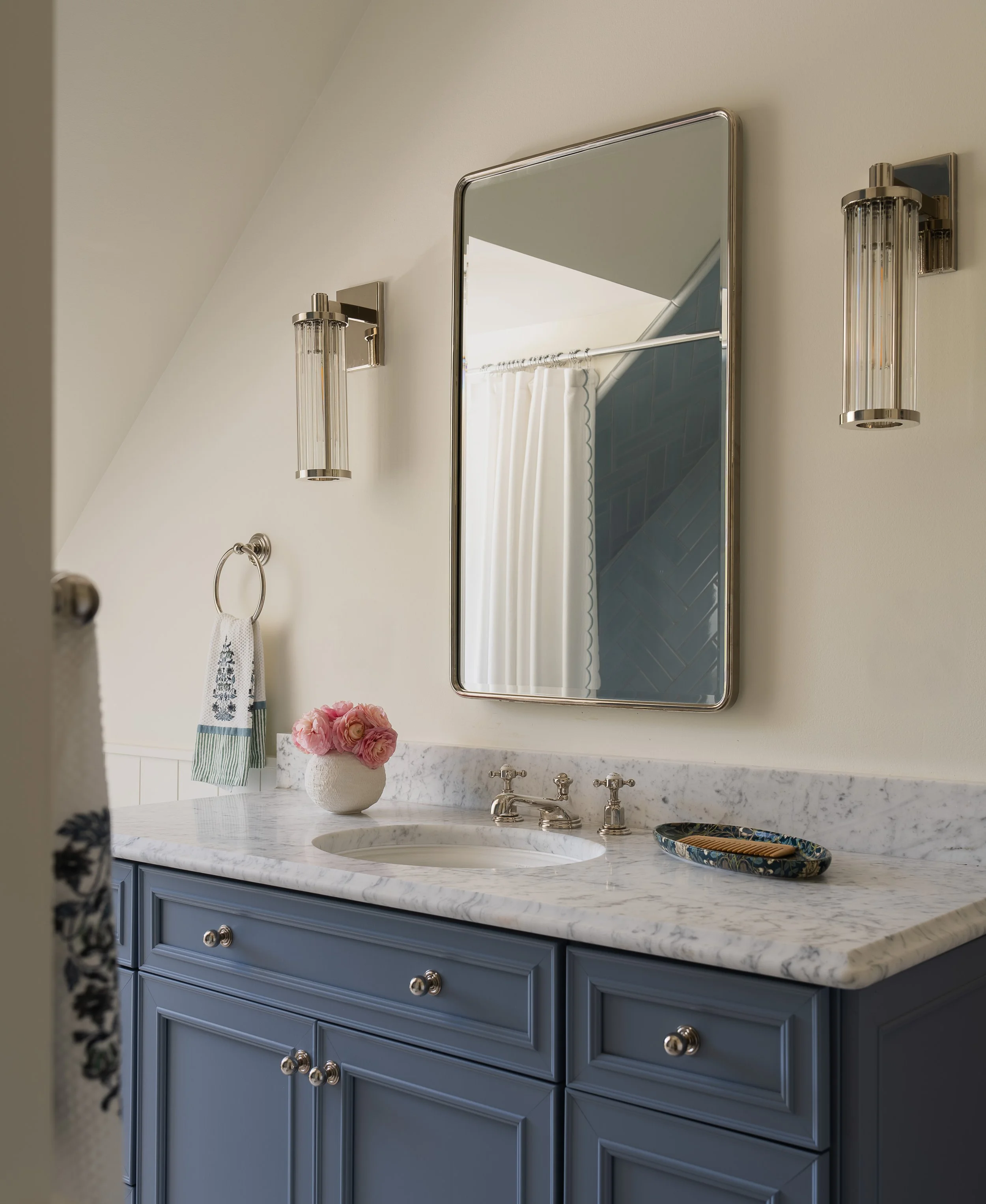 Restroom with marble sink, dark blue-gray drawers, and rectangular mirror.