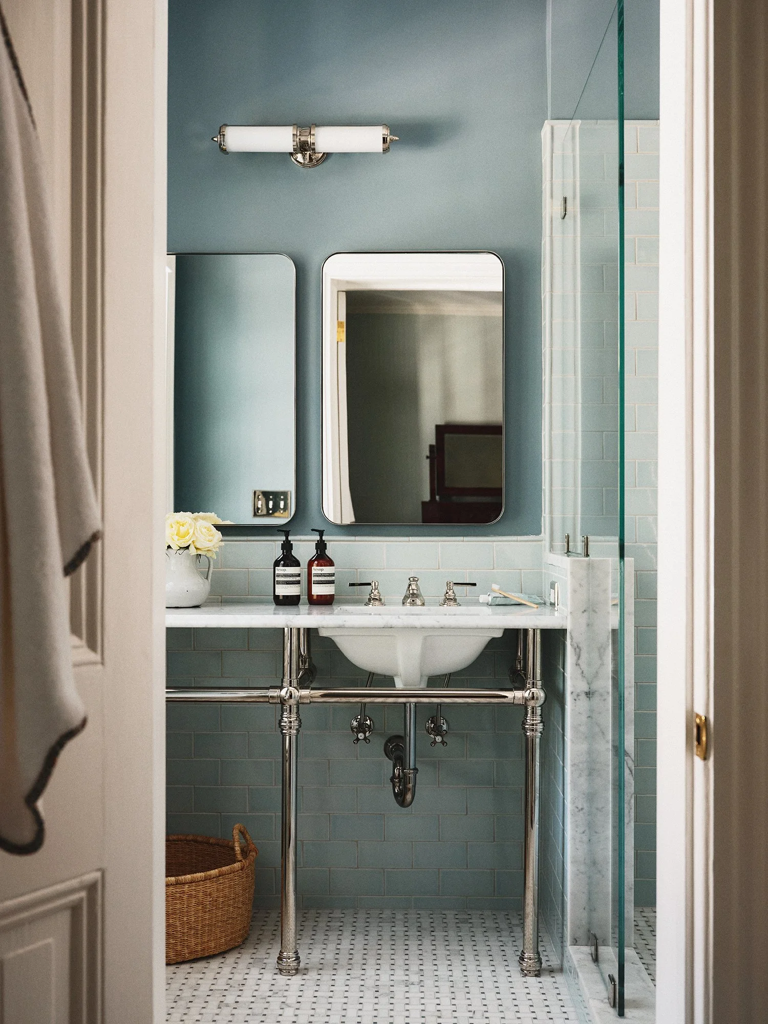 Restroom with teal walls, rectangular mirror, sink, and shower.