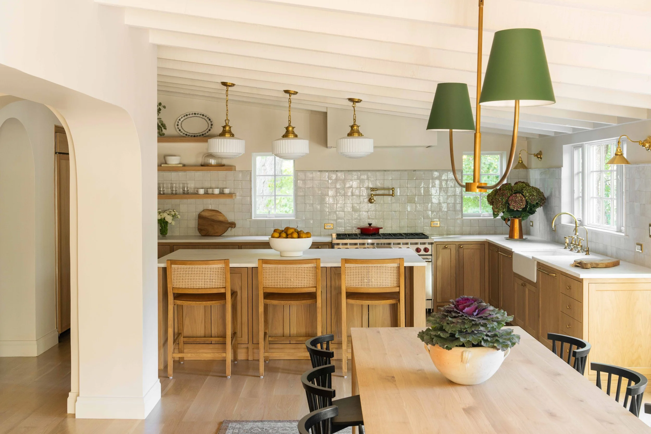 Open kitchen and dining area with a large island, stools, and green lamps.