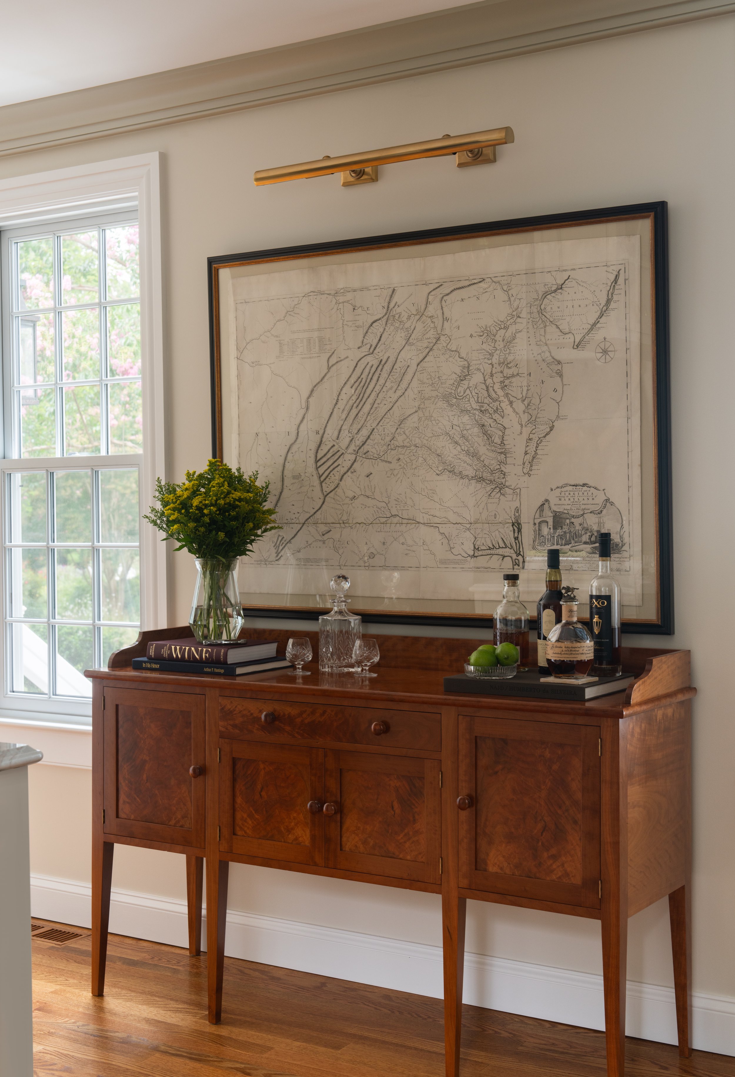 Wooden console with decorative books, plant vase, and drinking glasses.