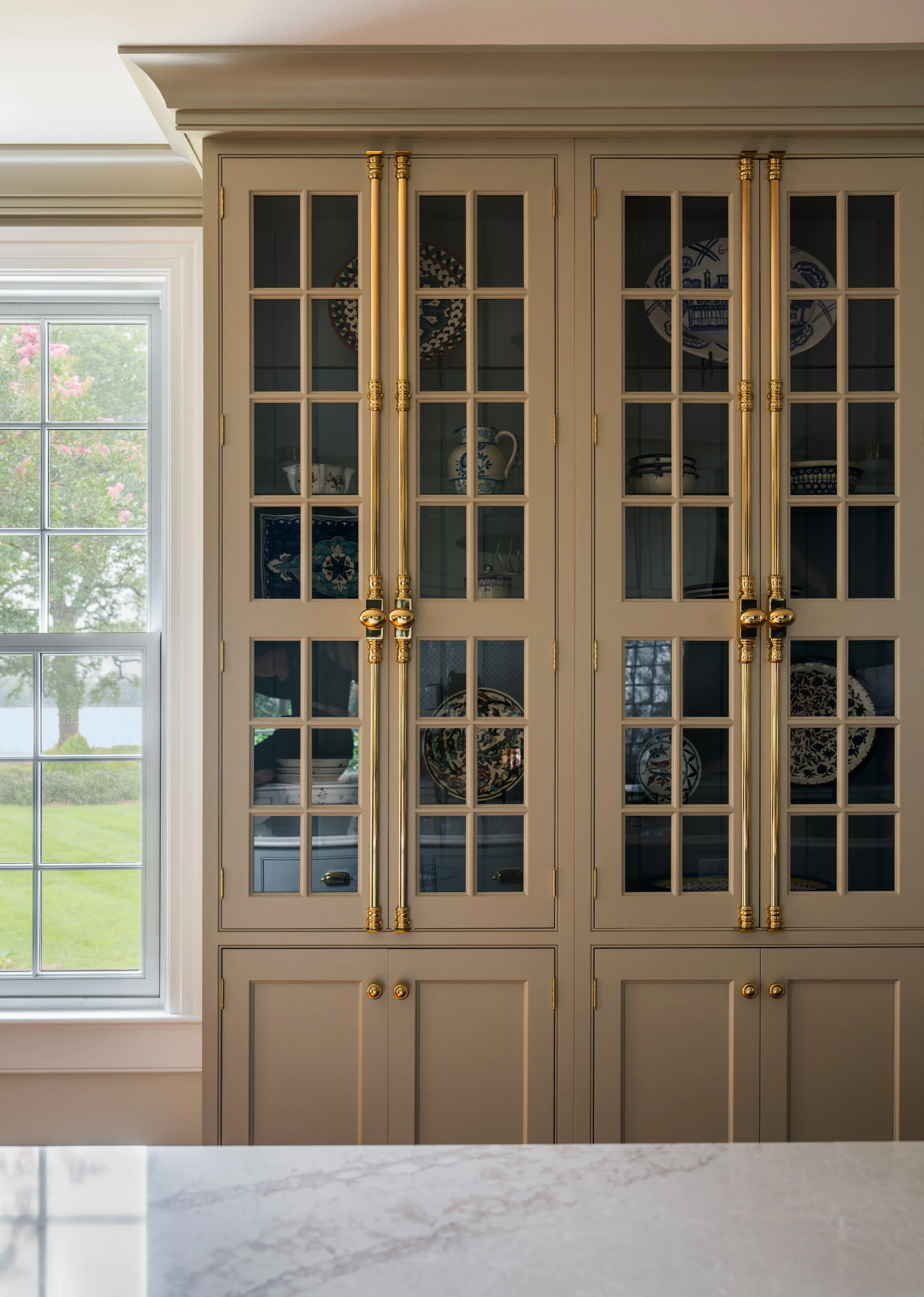 Dark beige kitchen display cabinets with brass hardware.