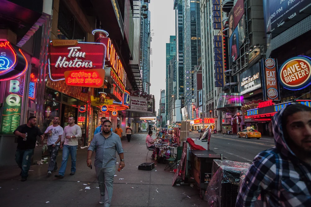 John, who sells photos to tourists, arrives in Times Square very early to set his table up for the day, while a few men leaving a bar stumble past 6:15 am.