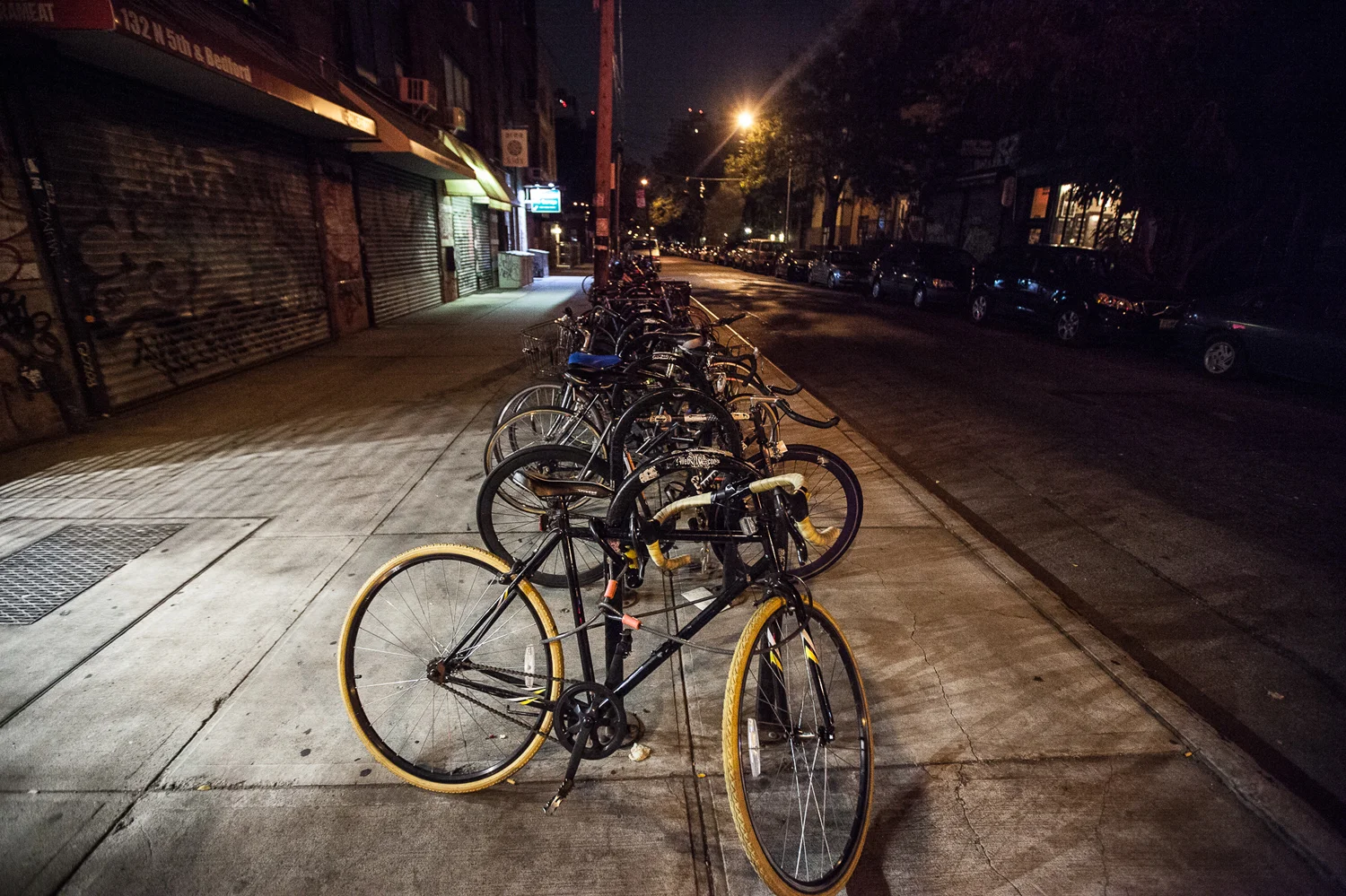 Bikes locked up off Bedford Ave in Williamsburg, Brooklyn. Normally a very busy sidewalk, sits empty at 6 am. 