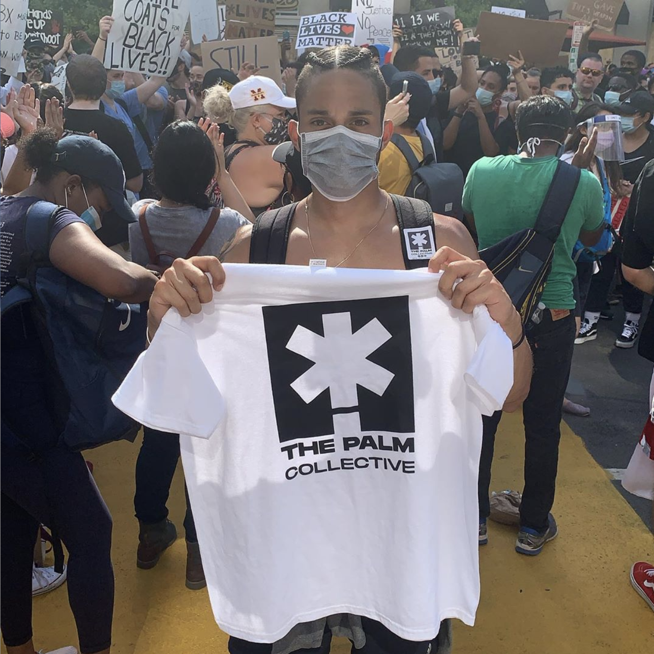 Photograph of a woman holding a Palm Collective t shirt at a protest 