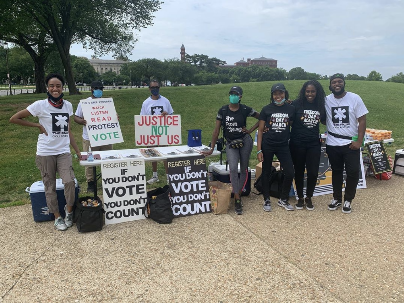  Photograph of Palm Collective volunteers standing at a voter registration table on the National Mall 