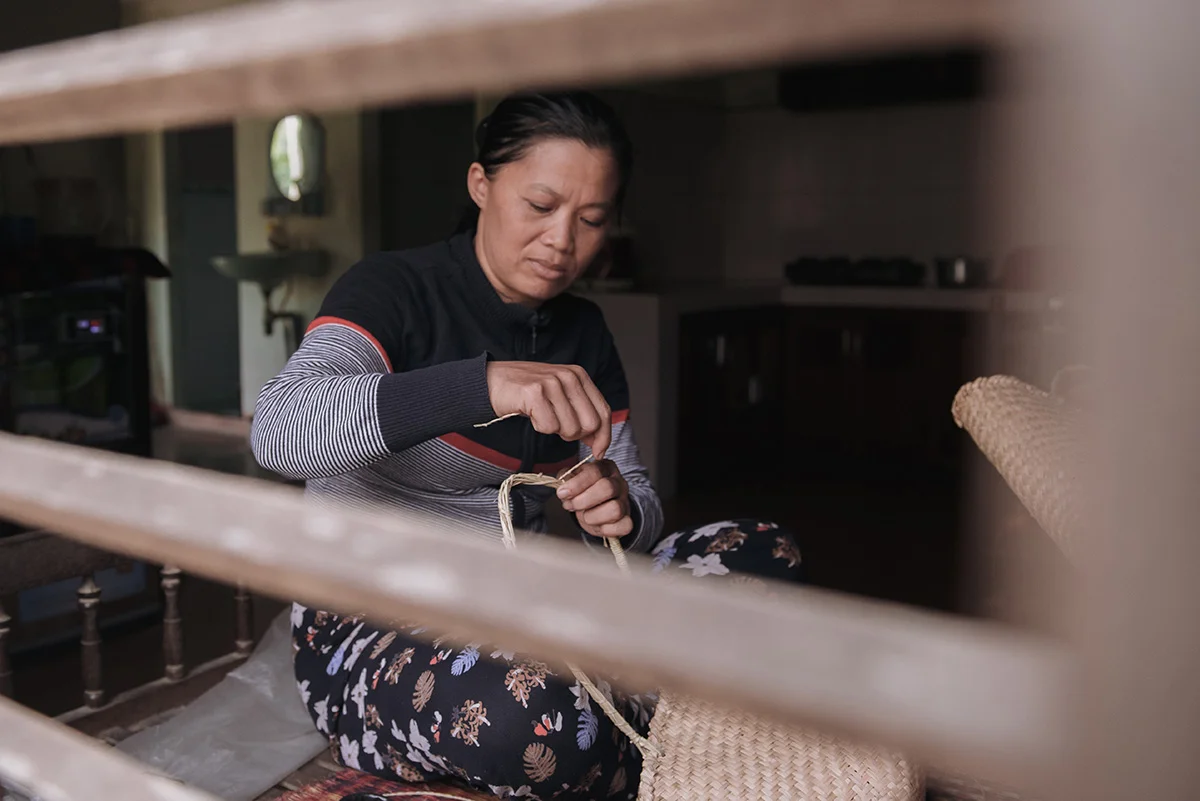 Hien working on one of the first prototype straw-weave bags. Photography by Ody.