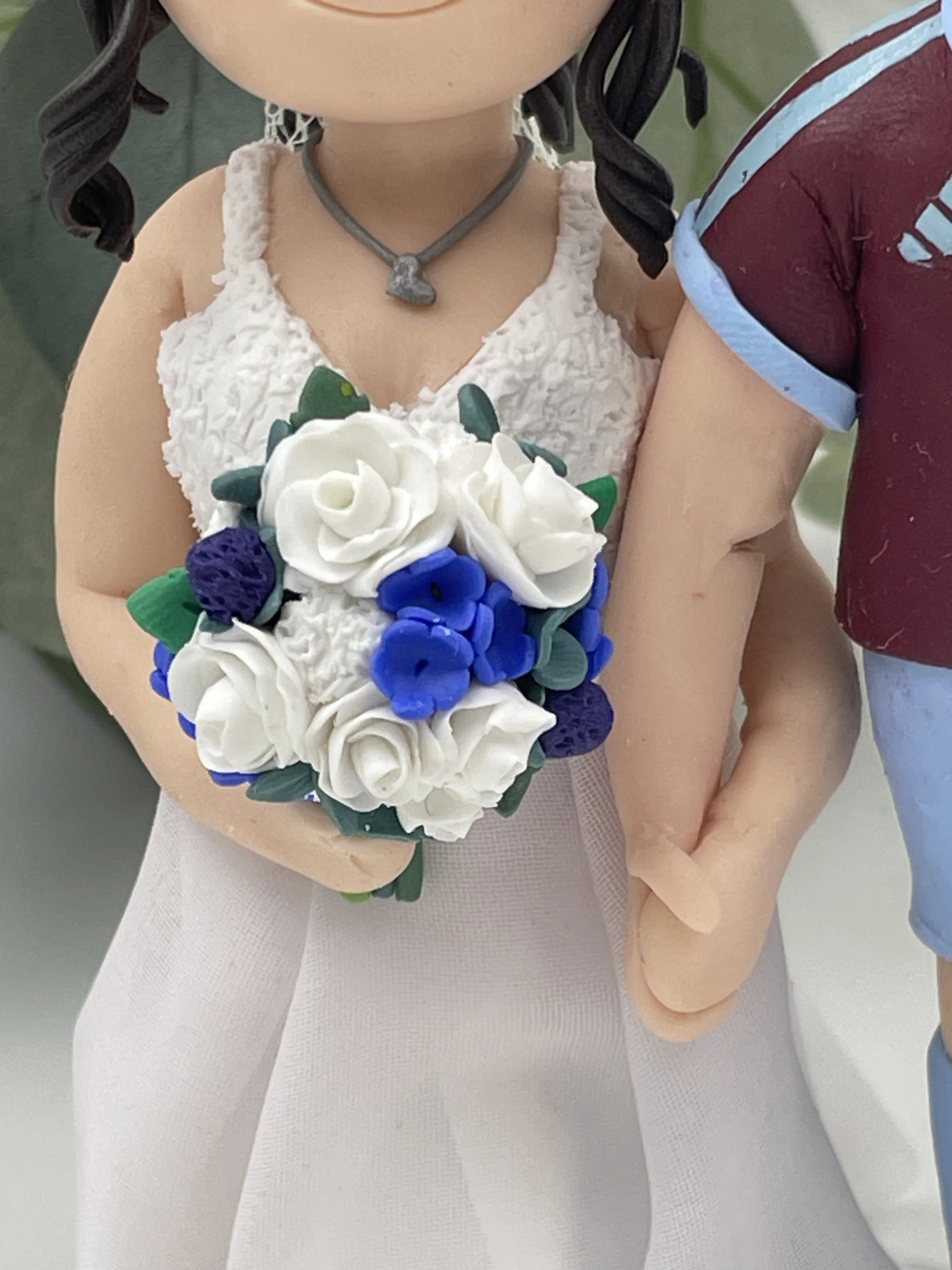 A polymer clay bridal bouquet featuring white roses and blue flowers