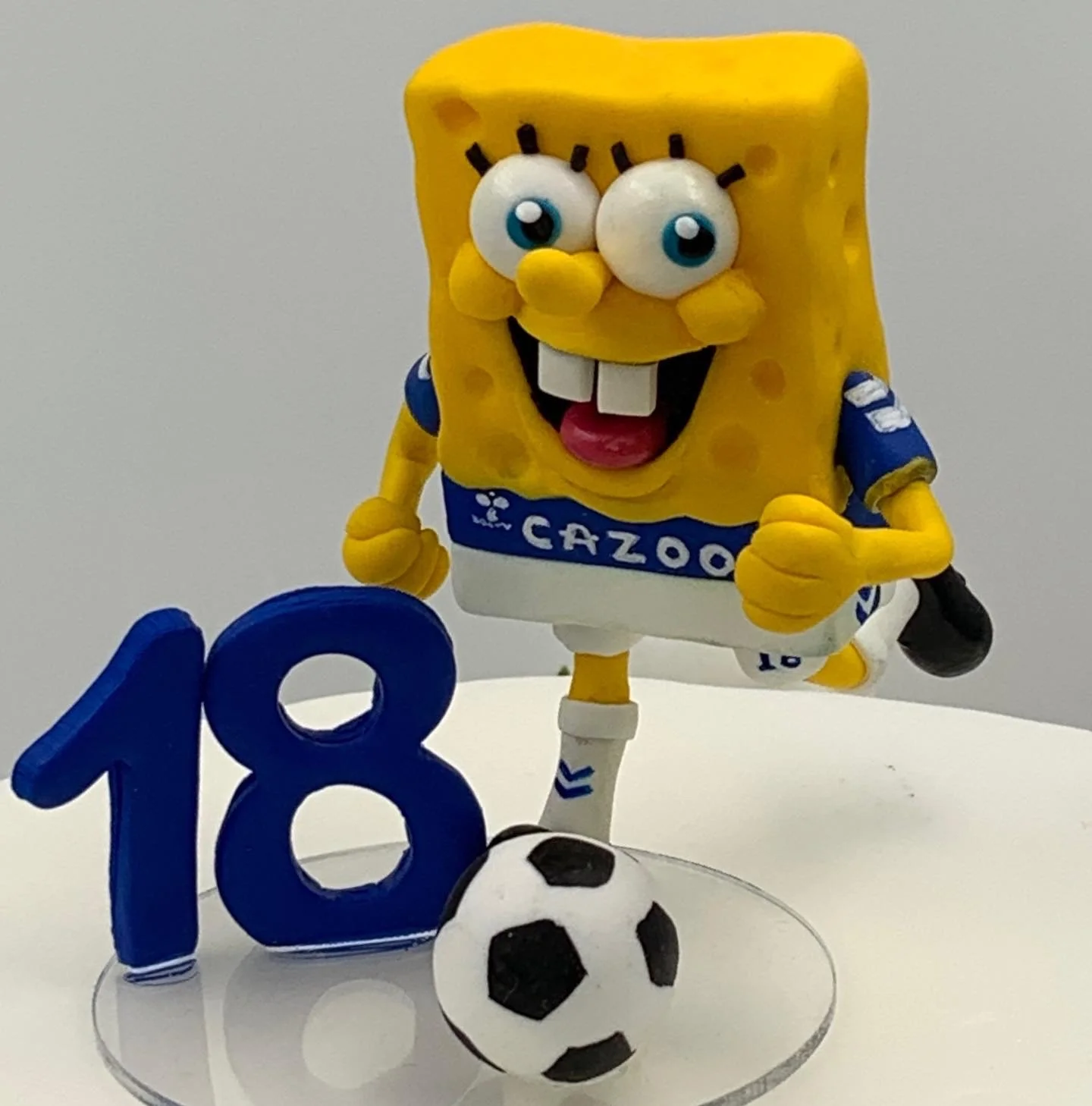 A clay 18th birthday cake topper of Spongebob Squarepants in a football kit