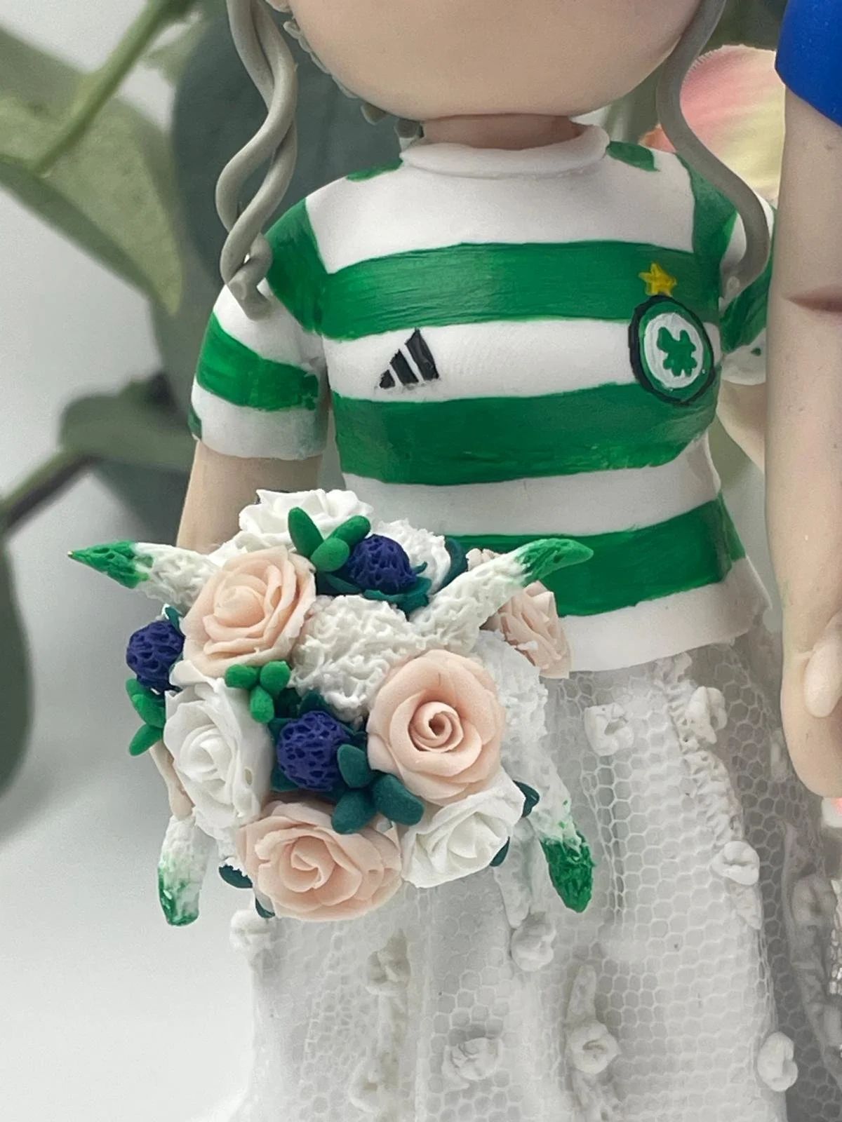 A close up of a bride's bouquet on a polymer clay wedding cake topper