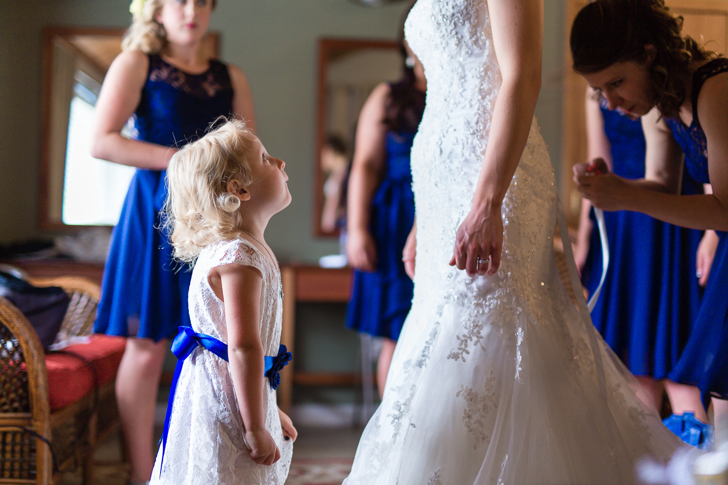 Flower girl looks up at bride in wedding dress