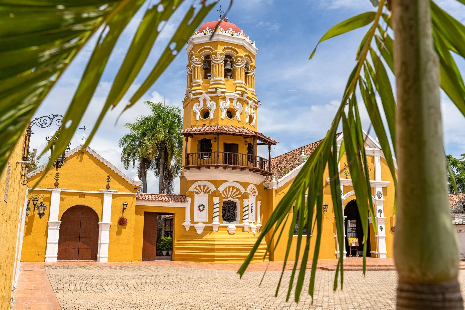  Iglesia de Santa Bárbara in Santa Cruz de Mompox, eingerahmt von Palmenblättern und mit ihrem charakteristischen achteckigen Glockenturm. 