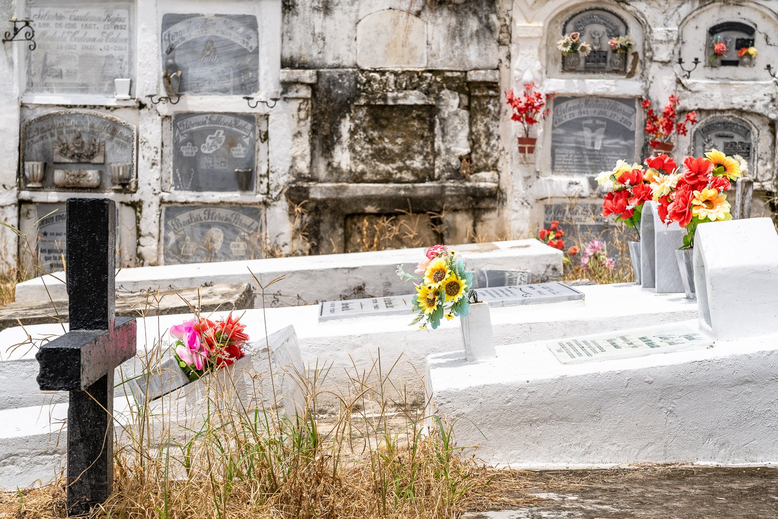  Historische Grabstätten auf dem Friedhof von Mompox, mit verwitterten Nischen und bunten Blumenarrangements. 