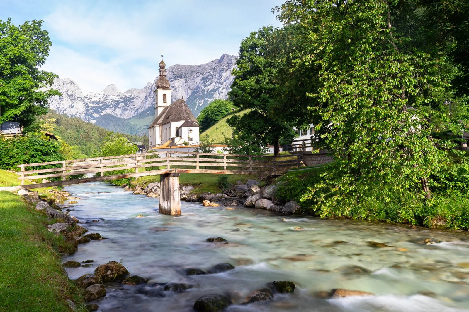  Pfarrkirche St. Sebastian in Ramsau im Berchtesgadener Land, Holzbrücke über die Ramsauer Ache vor Alpenkulisse 